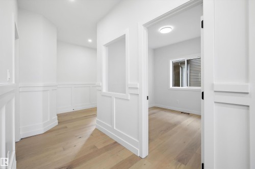 Hallway and room featuring light-colored wood flooring, white walls, and wainscoting - 34 Cannes Cove, St. Albert, AB - Indoor Photo Showing Other Room