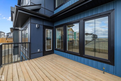 The property features an exterior deck with a wooden surface and black metal railings, complemented by blue siding - 34 Cannes Cove, St. Albert, AB - Outdoor With Deck Patio Veranda With Exterior