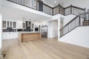 Open concept interior featuring hardwood floors, a kitchen with white cabinetry and a light wood island, and a staircase with dark wood railings - 34 Cannes Cove, St. Albert, AB  - Indoor Photo Showing Other Room 
