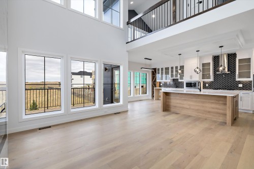 This property features an open-concept living space with light wood flooring, large windows, and a modern kitchen - 34 Cannes Cove, St. Albert, AB - Indoor