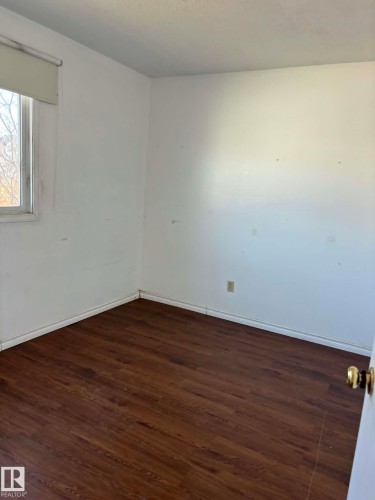 Room featuring wood-finish flooring, white baseboards, a white wall finish, and a window with a roller shade - 4129 134A Avenue Nw, Edmonton, AB - Indoor Photo Showing Other Room