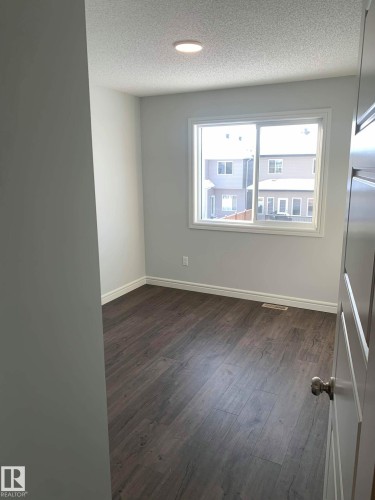 Room featuring wood-finish flooring, a white-framed window, recessed ceiling lighting, and white baseboards - 4129 134A Avenue Nw, Edmonton, AB - Indoor Photo Showing Other Room