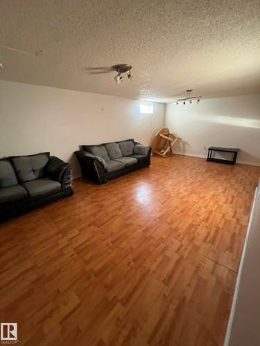 Spacious room featuring wood-finish flooring, white walls, and a textured ceiling - 4129 134A Avenue Nw, Edmonton, AB - Indoor