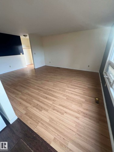 Open-concept living area featuring wood-finish flooring, white painted walls, and a window providing natural light - 4129 134A Avenue Nw, Edmonton, AB - Indoor Photo Showing Other Room