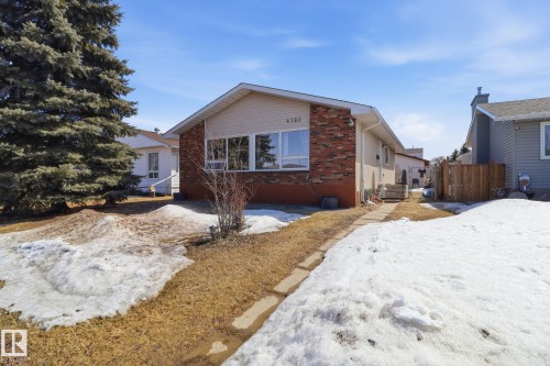 The property features a brick and siding exterior, with a large evergreen tree in the front yard - 4129 134A Avenue Nw, Edmonton, AB - Outdoor