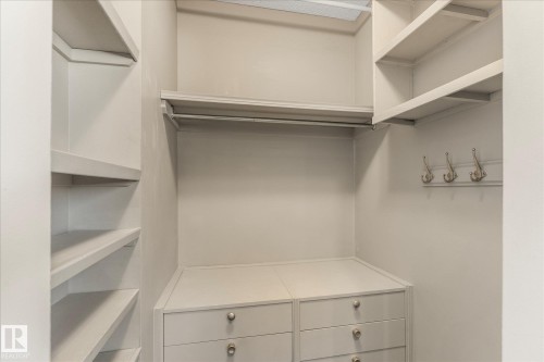Walk-in closet featuring white built-in shelving, hanging rods, and a dresser with drawers and round silver pulls - 2626 49 Street, Edmonton, AB - Indoor With Storage