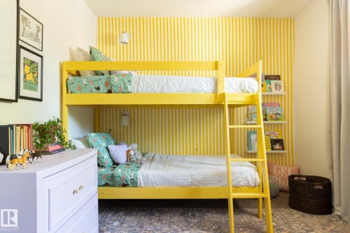This bright room features a striped accent wall and a bunk bed with a ladder - 2626 49 Street, Edmonton, AB - Indoor Photo Showing Bedroom