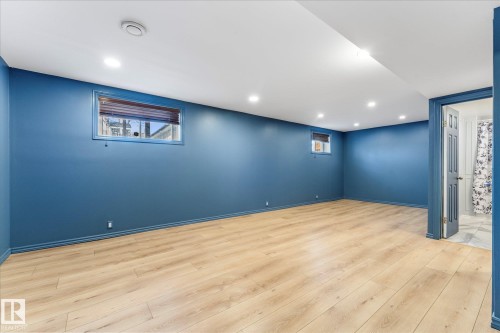 This spacious room features light wood-style flooring, recessed lighting, and windows with blinds - 2626 49 Street, Edmonton, AB - Indoor