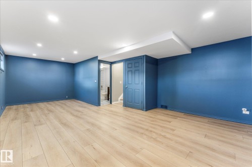 Spacious interior room featuring light-toned flooring, deep blue walls, recessed lighting, and a window - 2626 49 Street, Edmonton, AB - Indoor Photo Showing Other Room