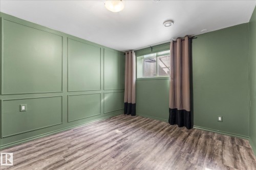 This room features a decorative paneled wall, wood-style flooring, and a window with blinds and curtains - 2626 49 Street, Edmonton, AB - Indoor Photo Showing Other Room