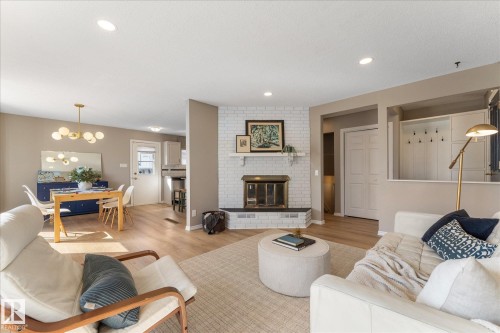 This property features light wood flooring throughout, a white brick fireplace with a mantel, and recessed lighting in the ceiling - 2626 49 Street, Edmonton, AB - Indoor Photo Showing Living Room With Fireplace