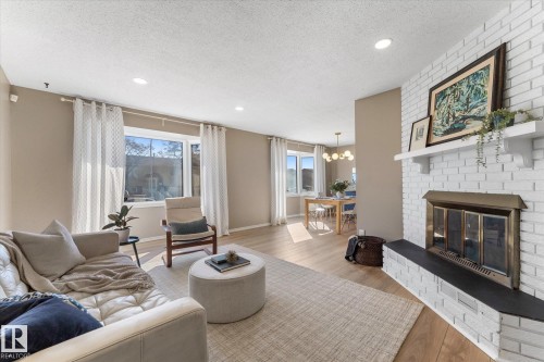 The living area features a white brick fireplace with a black hearth, recessed lighting, and light-colored flooring - 2626 49 Street, Edmonton, AB - Indoor Photo Showing Living Room With Fireplace