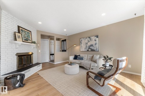 Living room featuring light-toned flooring, a white brick fireplace with a mantle, and recessed ceiling lighting - 2626 49 Street, Edmonton, AB - Indoor Photo Showing Living Room With Fireplace