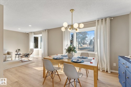 The living and dining area features light-toned flooring, large windows with drapes, and recessed lighting - 2626 49 Street, Edmonton, AB - Indoor Photo Showing Dining Room