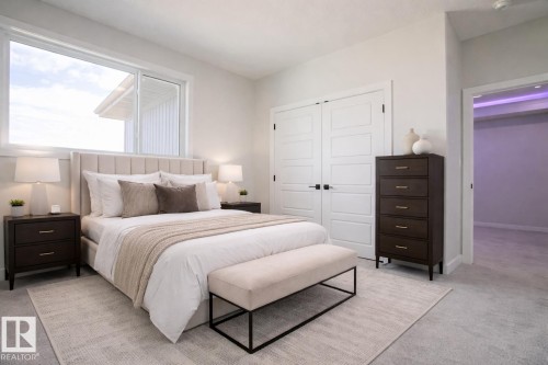 This bedroom features a large window providing ample natural light, a neutral color palette, and light-colored carpeting - Rural Leduc County, AB - Indoor Photo Showing Bedroom