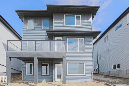 The property features a contemporary exterior with multi-level siding and a second-story balcony with a glass railing - Rural Leduc County, AB - Outdoor