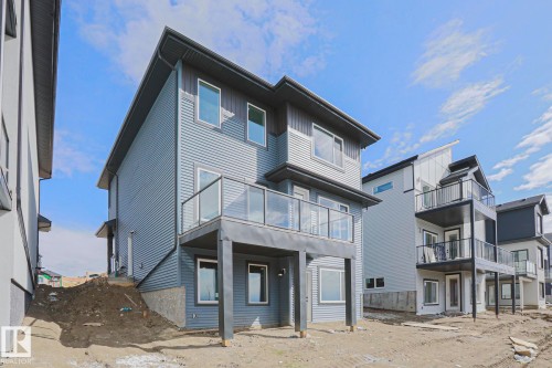 The property features a contemporary exterior with corrugated siding and a second-story deck with glass railings - Rural Leduc County, AB - Outdoor