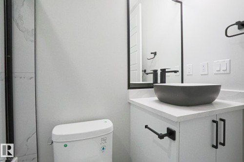Bathroom featuring a dark vessel sink, a light countertop, and a vanity with dark hardware - Rural Leduc County, AB - Indoor Photo Showing Bathroom