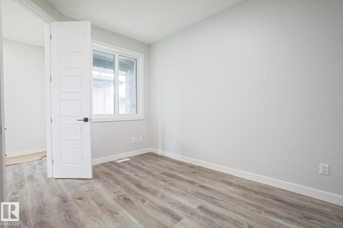 Room featuring light-colored walls, wood-style flooring, and a window providing natural light - Rural Leduc County, AB - Indoor Photo Showing Other Room