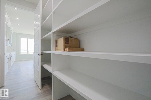 The property features extensive white built-in shelving, providing generous storage - Rural Leduc County, AB - Indoor Photo Showing Other Room