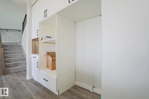 This entry area features built-in white cabinetry with black hardware, providing storage solutions - Rural Leduc County, AB - Indoor Photo Showing Other Room