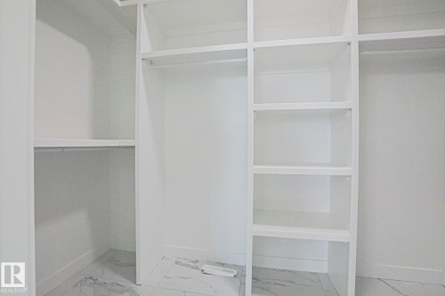 The property features a closet with built-in shelving, hanging rods, and a light-colored tiled floor - Rural Leduc County, AB - Indoor With Storage