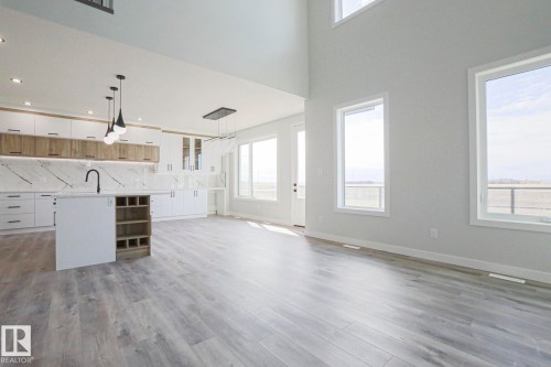 Open concept living area featuring light wood-style flooring and high ceilings - Rural Leduc County, AB - Indoor