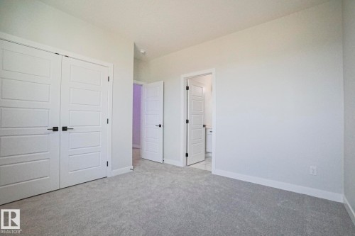 The room features light gray carpeting, white walls, and white trim - Rural Leduc County, AB - Indoor Photo Showing Other Room