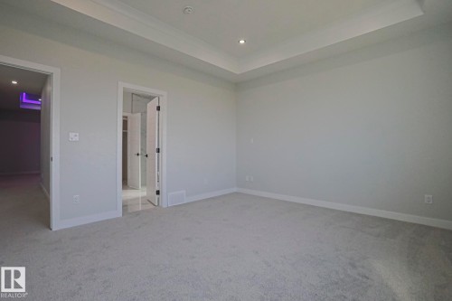 Spacious room featuring light grey carpeting, white walls, and a tray ceiling with recessed lighting - Rural Leduc County, AB - Indoor Photo Showing Other Room