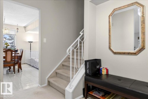 The property features a staircase with carpeted treads and a white railing, alongside a wall-mounted octagonal mirror with a decorative frame - 391 Lee Ridge Road, Edmonton, AB - Indoor Photo Showing Other Room