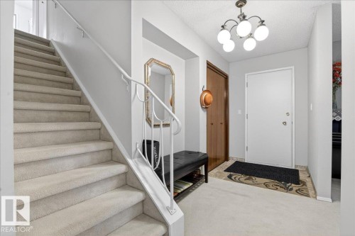 Entryway featuring a staircase with carpeted treads and a metal railing, a front door, and a light fixture - 391 Lee Ridge Road, Edmonton, AB - Indoor Photo Showing Other Room