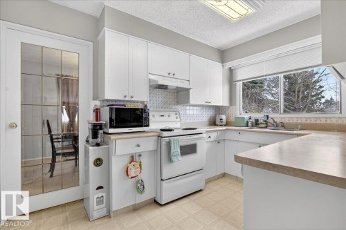 The kitchen features white cabinetry, a large window, and an overhead light fixture - 391 Lee Ridge Road, Edmonton, AB - Indoor Photo Showing Kitchen