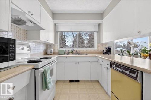 The kitchen features white cabinetry, a U-shaped countertop, and a window above the sink - 391 Lee Ridge Road, Edmonton, AB - Indoor Photo Showing Kitchen With Double Sink