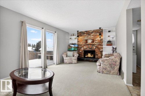 Living room featuring light-colored carpeting, a brick fireplace with a hearth, and built-in shelving with accent lighting - 391 Lee Ridge Road, Edmonton, AB - Indoor Photo Showing Living Room With Fireplace