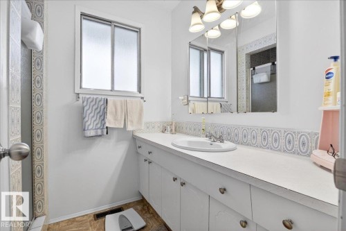 The bathroom features a window with frosted glass, a vanity with a white countertop and integrated sink, cabinet storage, and a mirror with overhead lighting - 391 Lee Ridge Road, Edmonton, AB - Indoor Photo Showing Bathroom