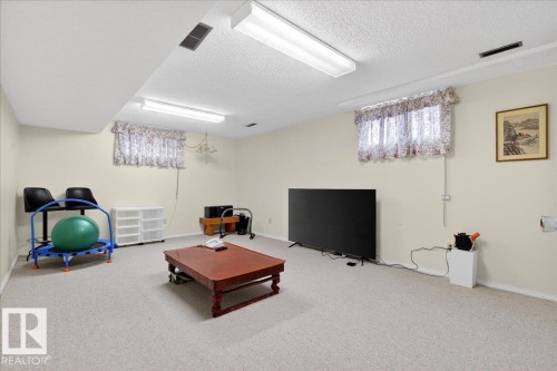 The property features a spacious room with light-colored carpeting, white walls, and a dropped ceiling with fluorescent lighting - 391 Lee Ridge Road, Edmonton, AB - Indoor