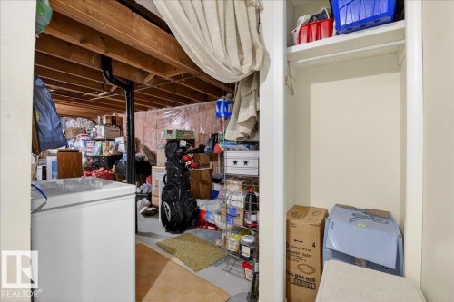 The property offers a storage area with exposed ceiling joists and a white chest freezer - 391 Lee Ridge Road, Edmonton, AB - Indoor