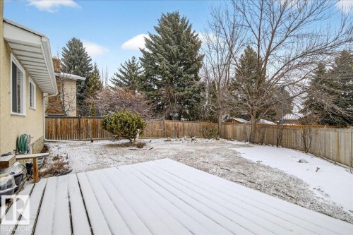 The property features a large deck overlooking a spacious yard with mature trees and a wooden fence - 391 Lee Ridge Road, Edmonton, AB - Outdoor