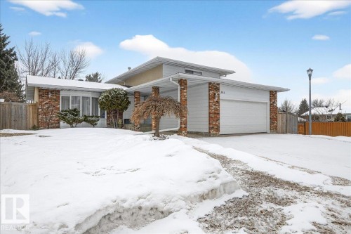 The property features a brick and siding exterior, an attached garage, a paved driveway, and a front yard with mature trees and shrubbery - 391 Lee Ridge Road, Edmonton, AB - Outdoor