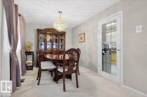Dining area featuring light-colored carpeting, a crystal chandelier, and a white door with glass panels - 391 Lee Ridge Road, Edmonton, AB - Indoor Photo Showing Dining Room