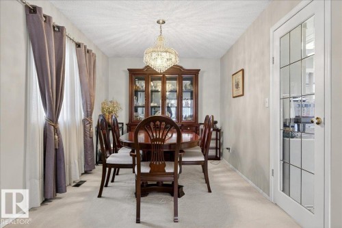 This dining area features a chandelier, light-colored carpeting, and a glass-paneled door - 391 Lee Ridge Road, Edmonton, AB - Indoor Photo Showing Dining Room