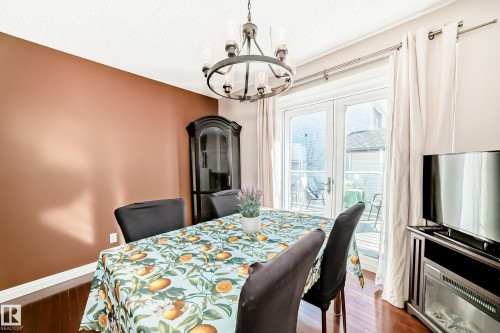 Dining area featuring hardwood floors, a modern chandelier, and access to an outdoor area through double doors - 287 Lago Lindo Crescent, Edmonton, AB - Indoor Photo Showing Dining Room