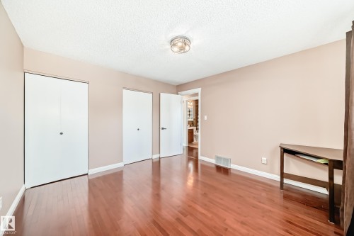 This room features polished hardwood flooring, a ceiling-mounted light fixture, and two white closet doors - 287 Lago Lindo Crescent, Edmonton, AB - Indoor Photo Showing Other Room