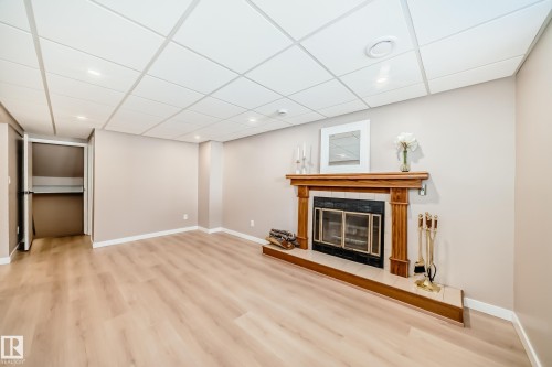 Spacious room with light-toned flooring, a fireplace featuring a wooden mantelpiece, and a drop ceiling with recessed lighting - 287 Lago Lindo Crescent, Edmonton, AB - Indoor With Fireplace
