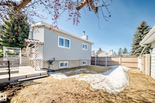 The property features a spacious backyard with a deck, a wooden fence, and mature evergreen trees - 287 Lago Lindo Crescent, Edmonton, AB - Outdoor