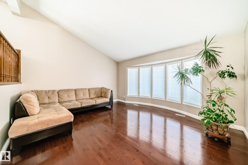 Living space featuring rich hardwood flooring, a vaulted ceiling, and a large bay window with frosted glass - 287 Lago Lindo Crescent, Edmonton, AB - Indoor Photo Showing Other Room