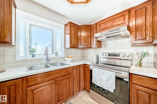 Well-appointed kitchen featuring wood cabinetry, a double basin sink, stainless steel appliances, and a tiled backsplash - 287 Lago Lindo Crescent, Edmonton, AB - Indoor Photo Showing Kitchen With Double Sink