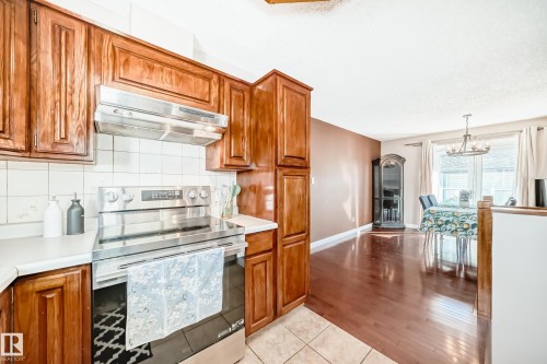 The kitchen features wooden cabinetry, white countertops, and a stainless steel electric range - 287 Lago Lindo Crescent, Edmonton, AB - Indoor Photo Showing Kitchen