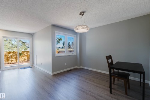 This area features light wood-style flooring, a window offering natural light, and a sliding glass door providing access to the exterior - 17308 61 Avenue, Edmonton, AB - Indoor