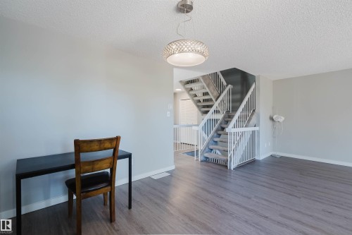 Living area featuring wood-style flooring, a decorative overhead light fixture, and a staircase with white railings - 17308 61 Avenue, Edmonton, AB - Indoor Photo Showing Other Room